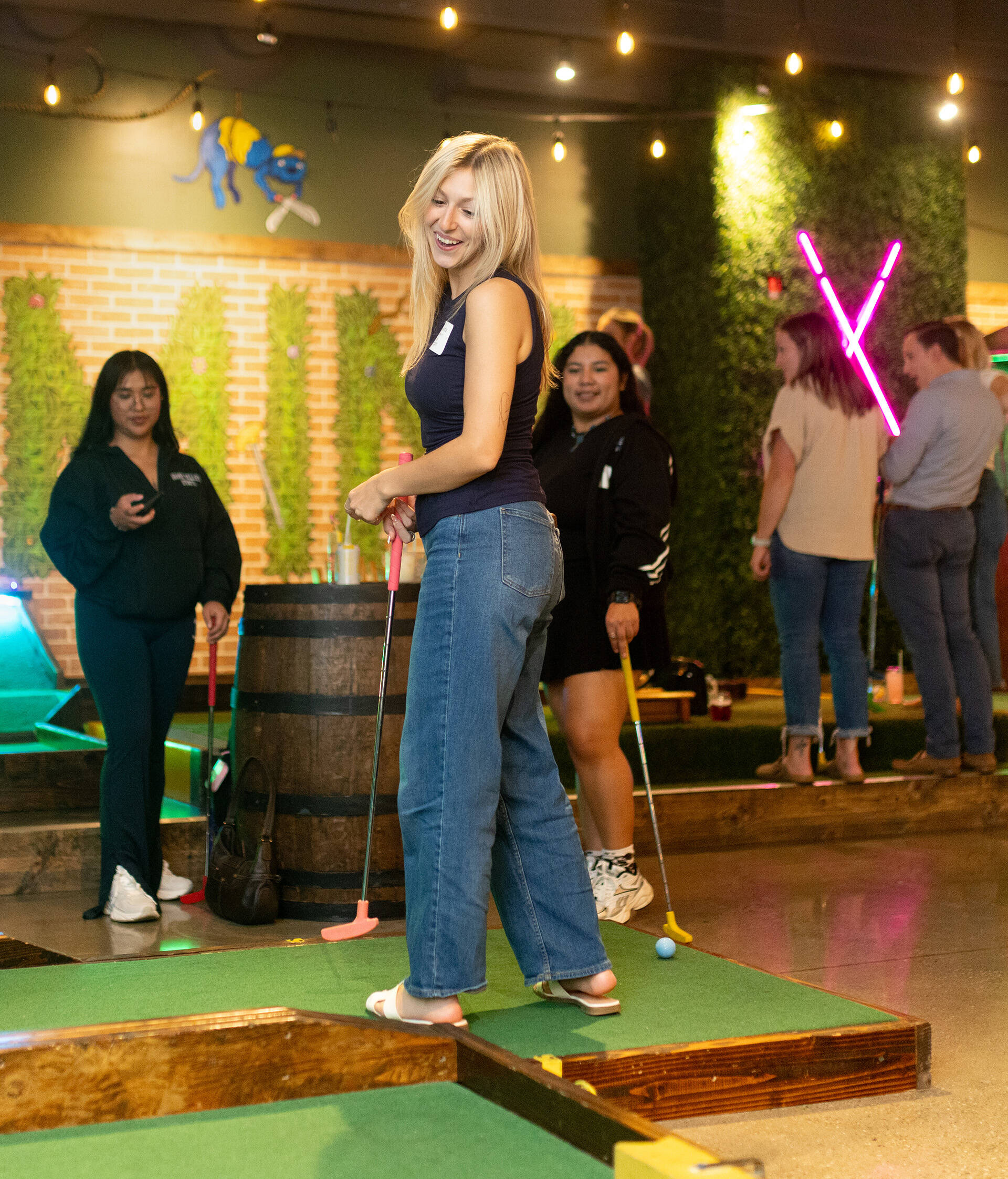 Blonde woman at an indoor mini golf course